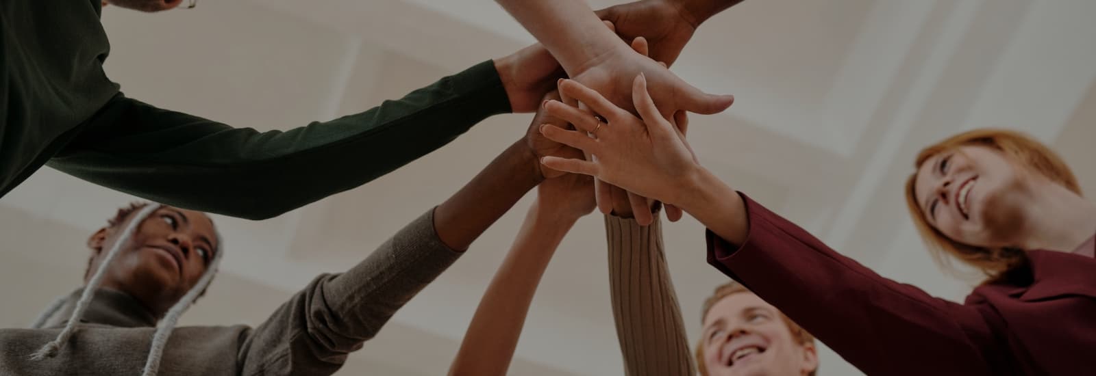 groupe de personnes en cercle dont les mains se rejoignent en signe de cohésion