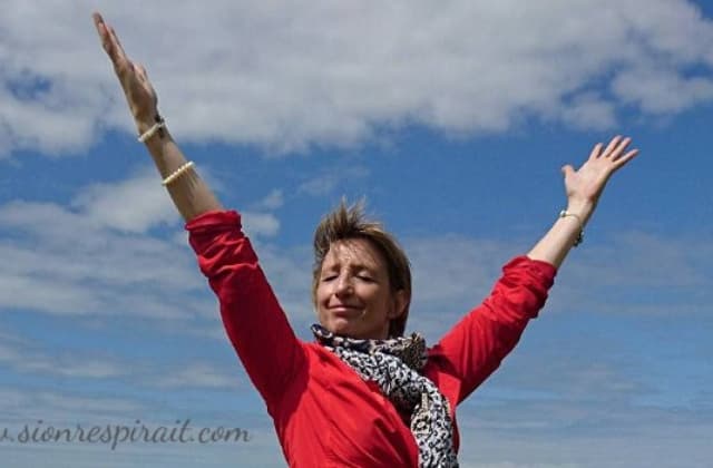 marie-catherine adeline, les bras levés vers le ciel au bord de mer